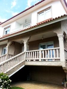 uma grande casa branca com uma varanda em Apartamento Sanxenxo - Playa Areas em Sanxenxo