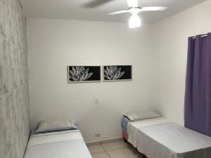 duas camas num quarto com duas fotografias na parede em Pousada Hostel Universitário em Londrina