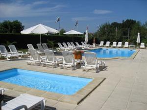 a group of chairs and a pool with chairs and umbrellas at la ferme des 4 chenes in Urt