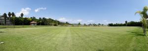 a large field of grass with a building and trees at Jardín Cerritos Xochitepec in Xochitepec