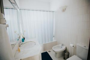 a white bathroom with a sink and a toilet at Vila Luis Mendes in Ribeira Brava