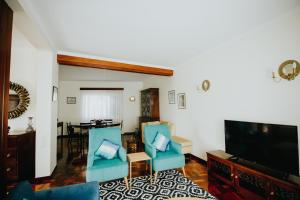 a living room with blue chairs and a flat screen tv at Vila Luis Mendes in Ribeira Brava