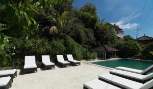 a group of lounge chairs next to a swimming pool at Baliku Dive Resort in Amed