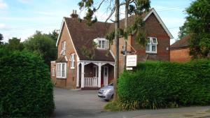 a brick house with a car parked in the driveway at Masslink Guest House in Horley