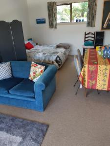 a living room with a blue couch and a bed at Murrays On Mary in Whangamata