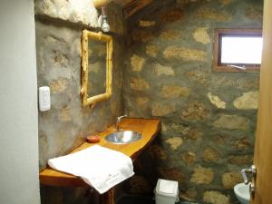 a stone bathroom with a sink and a mirror at Alauri Ñire in Huinganco