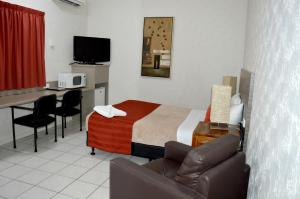 a small hotel room with a bed and a desk at Mid City Motor Inn in Gladstone