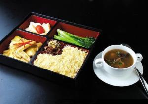 a lunch box with a cup of soup and rice at Dunhuang Season Boutique Hotel in Dunhuang
