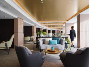 シドニーにあるThe Star Grand Hotel and Residences Sydneyの椅子とテーブルのあるロビーを歩く女性
