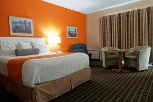 a hotel room with a bed and a table and chairs at Howard Johnson by Wyndham Tillsonburg in Tillsonburg