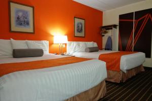 two beds in a hotel room with orange walls at Howard Johnson by Wyndham Tillsonburg in Tillsonburg