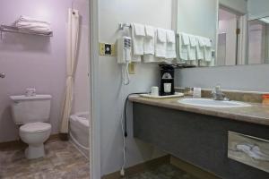 een badkamer met een wastafel, een toilet en een spiegel bij Howard Johnson by Wyndham Tillsonburg in Tillsonburg