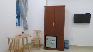 a kitchen with a small table and a cabinet and a refrigerator at Hoang Ngoc Hotel in Dĩ An