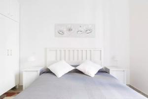 a white bedroom with a white bed with two pillows at Nobile Casa in Rome