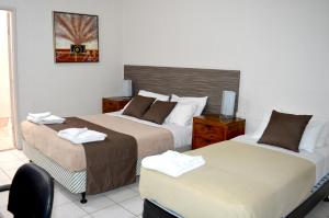 a hotel room with two beds and a chair at Mid City Motor Inn in Gladstone +15 photos