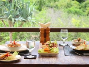 a wooden table with plates of food and wine glasses at Jeeva Beloam Beach Camp in Tanjung Ringgit