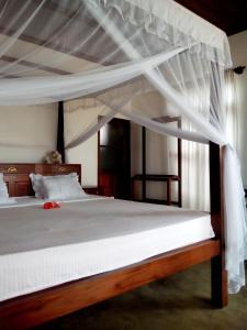 a bedroom with a large bed with white bedding at Thanu Beach Villa in Ambalangoda