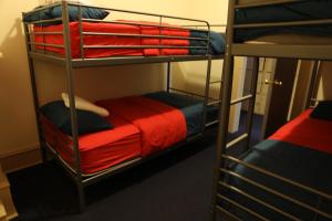 a room with three bunk beds with red sheets at Duo Nomad in Washington, D.C.