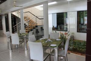 une salle à manger avec une table et des chaises blanches dans l'établissement Green Royale Resorts, à Bodināyakkanūr