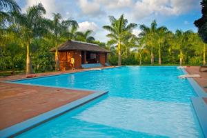 a swimming pool with a gazebo and palm trees at Red Earth Kabini in Begūr