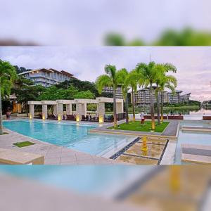 a large swimming pool with palm trees and buildings at Miranda 514B 2br at Pico de Loro by Raquel's Place in Nasugbu