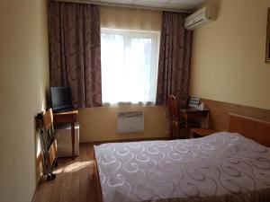 a bedroom with a bed and a window and a television at Sport Hotel in Slavyanka