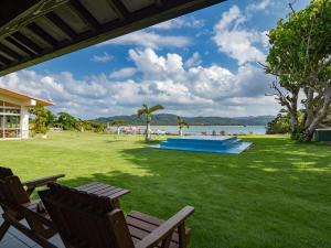 a lawn with two chairs and a swimming pool at Villa Unarizaki in Iriomote