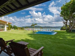 um relvado com duas cadeiras e uma piscina em Villa Unarizaki em Iriomote