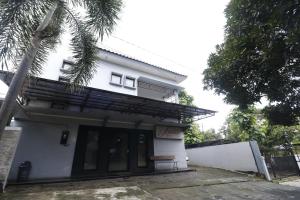 a white house with a palm tree in front of it at RedDoorz Plus near Undip Tembalang in Semarang