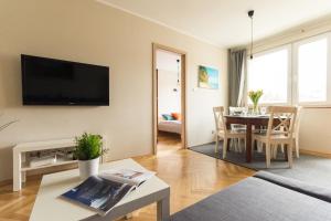 a living room with a table and a tv on a wall at Sea You Apartments- Malczewskiego in Sopot