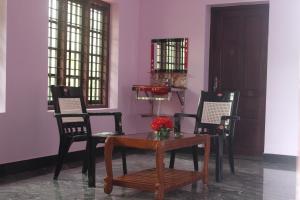 comedor con mesa, sillas y pared púrpura en Puthenchirayil Homestay en Thiruvananthapuram