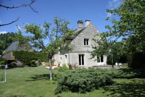 une vieille maison blanche avec un arbre dans la cour dans l'établissement L'eau vive, à Amblie