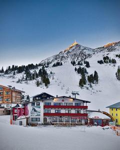 a building in the snow with a mountain in the background at Austria Alpinhotel Ski IN Ski OUT an der Edelweissbahn in Obertauern