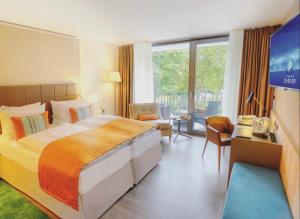 Habitación de hotel con cama grande y TV en FAVORITE Parkhotel en Mainz