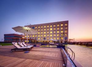 a hotel with chairs and an umbrella in front of a building at Balaji Sarovar Premiere in Solapur