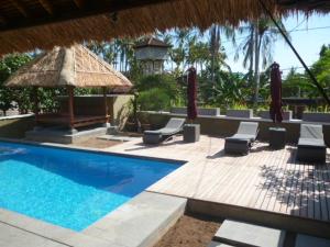 a swimming pool with chairs and a gazebo at Le Jardin in Amed