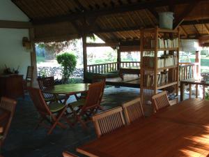 a room with tables and chairs and a library of books at Le Jardin in Amed