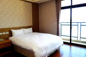 a bedroom with a white bed and a large window at Yi Da Lakeside Hotel in Yuchi