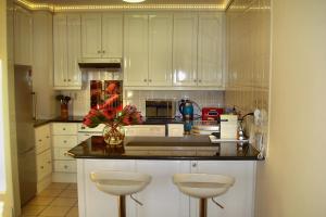a kitchen with white cabinets and a counter with two stools at WATERFRONT 15 QUAY WEST in Knysna