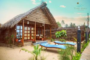 a house with a thatched roof and benches in front at The Bay Agonda in Agonda