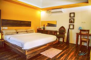 a bedroom with a bed and a desk and a chair at The Bay Agonda in Agonda