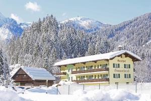 a building in the snow with snow covered trees at Gasthof Gosauschmied in Gosau