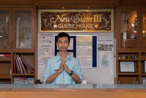 Ein Mann steht vor einem Tresen mit den Händen vor ihm. in der Unterkunft New Siam III Guest House in Bangkok
