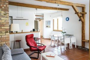 a living room with a table and a red chair at Ferienwohnung Design Apartment Seoul in Radolfzell am Bodensee