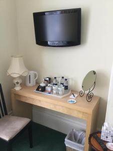 Habitación con mesa y TV en la pared. en The Swallow Hotel, en Bridlington