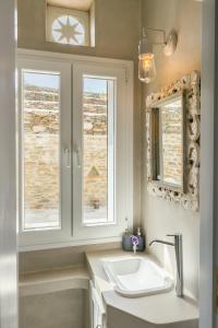 a bathroom with a sink and two windows at Imarkellis Boutique Villas in Pánormos