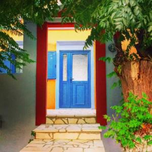eine blaue Tür auf einem Haus mit einem Baum in der Unterkunft Taxiarchis in Symi