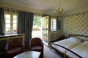 a bedroom with a bed and two chairs and a window at Hotel Park Villa in Heilbronn