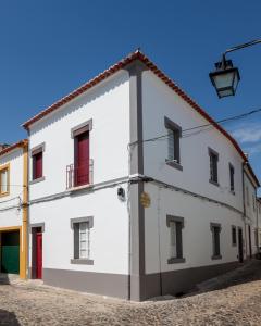 ein weißes Gebäude mit roten Türen auf einer Straße in der Unterkunft Alfar Aqueduct - Évora House in Évora