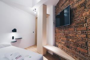 ビルバオにあるMoyua Apartment by People Rentalsのレンガの壁のベッドルーム(テレビ付)